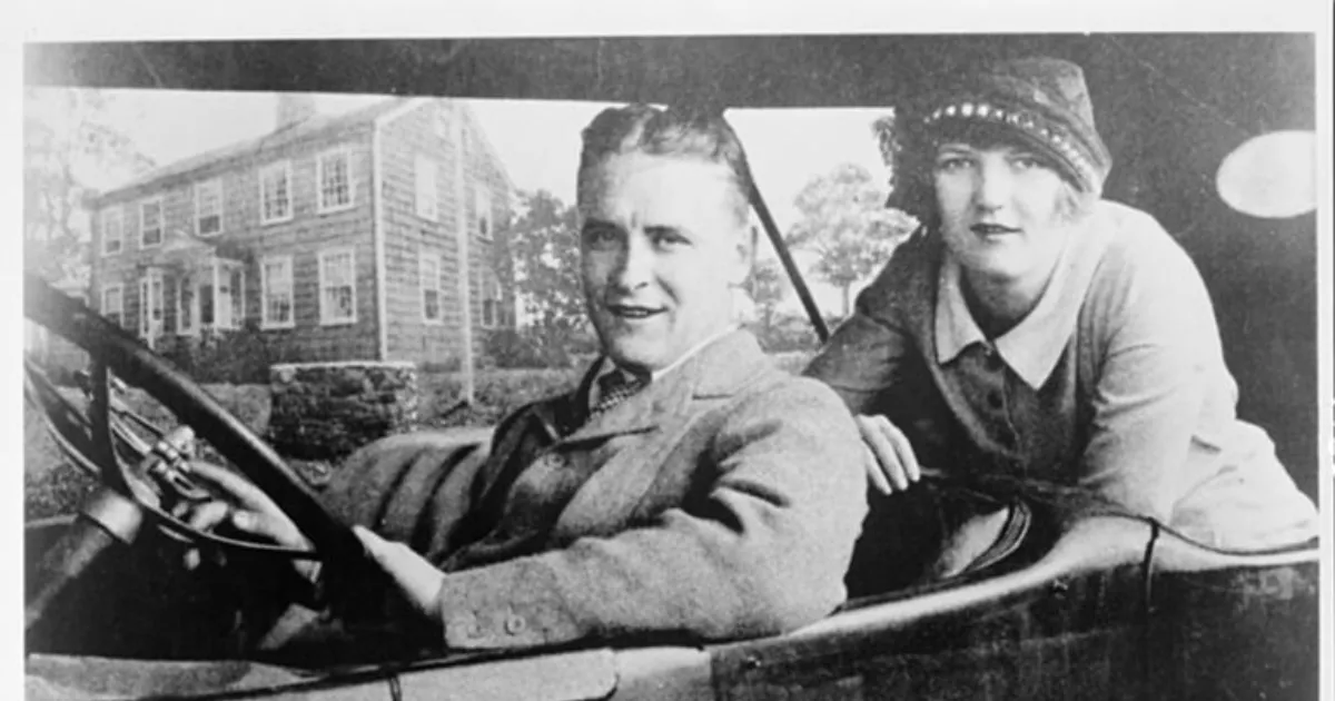 F. Scott Fitzgerald e Zelda Fitzgerald sentados em um carro diante de uma casa, em fotografia em preto e branco.