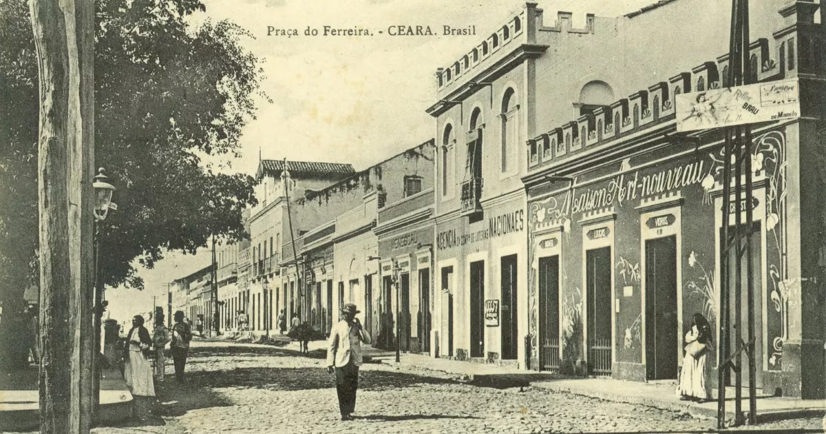 otografia histórica da rua comercial diante da Praça do Ferreira, em Fortaleza, com fachadas de lojas, calçamento de pedra e pedestres.
