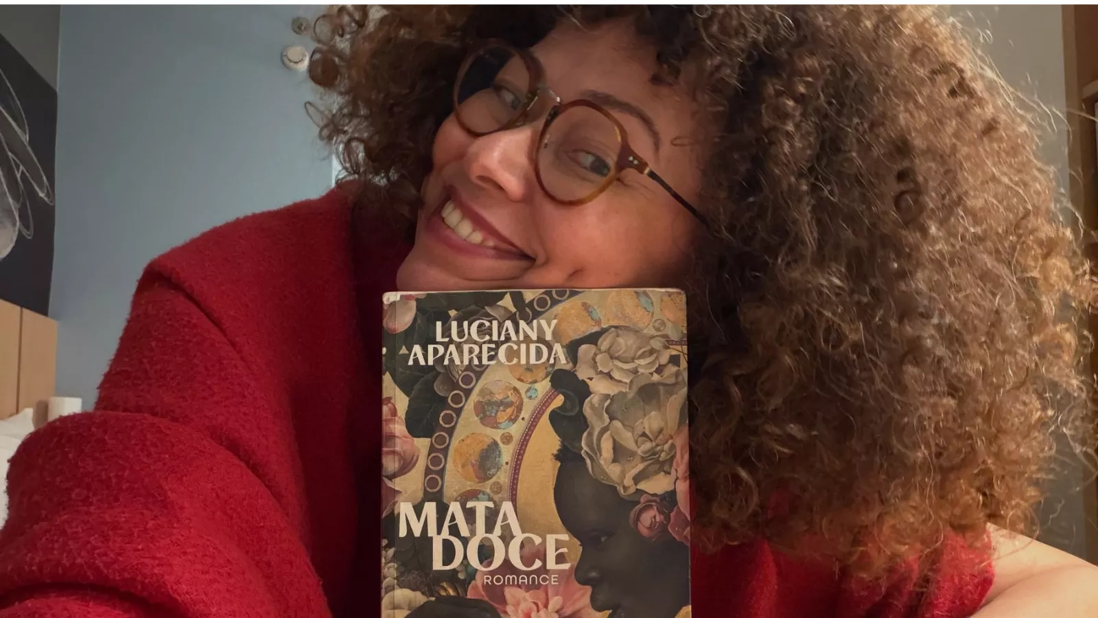 Luciany Aparecida sorri enquanto segura um exemplar de Mata Doce, romance publicado pela Alfaguara.