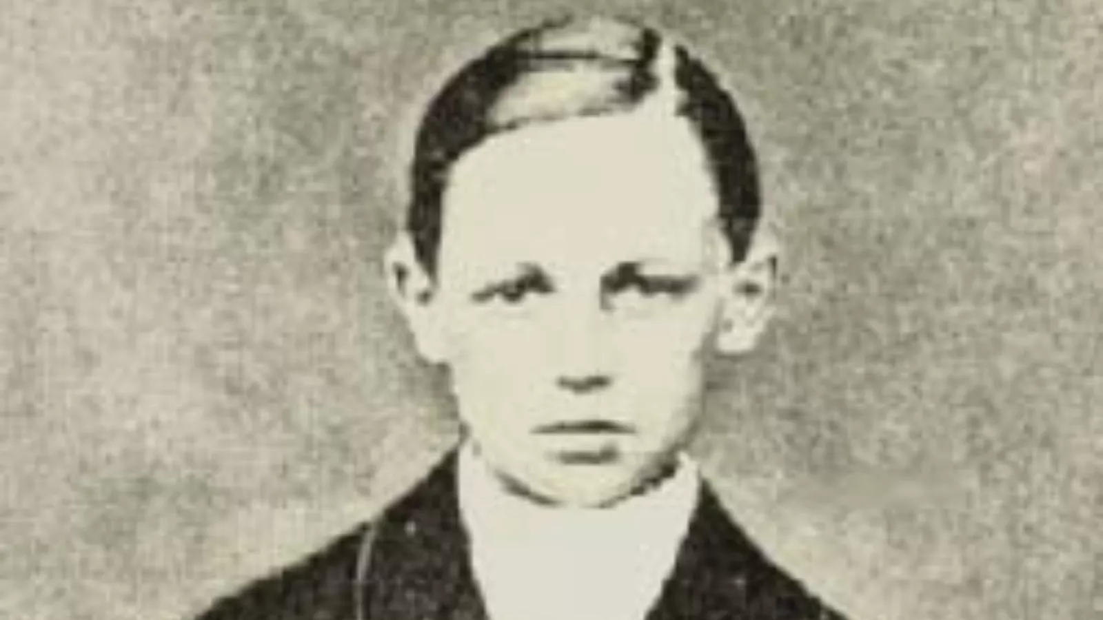 Fotografia antiga, em tons de cinza e bege, de Arthur Rimbaud menino, de frente. Ele tem cabelo curto e penteado, expressão séria e usa paletó escuro com camisa clara.