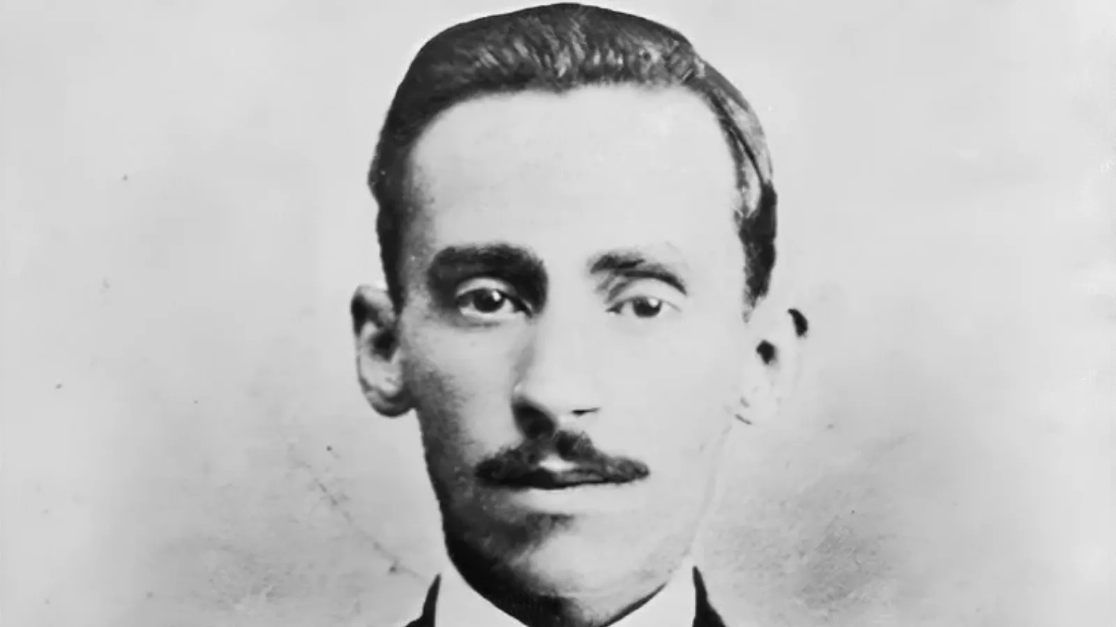 Retrato em preto e branco do poeta paraibano Augusto dos Anjos, de cabelo penteado para trás, bigode e terno escuro, autor de Eu, seu único livro