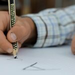 Criança escrevendo em um papel com um lápis - imagem para uma postagem sobre um plano de aula a respeito de Poesia Visual