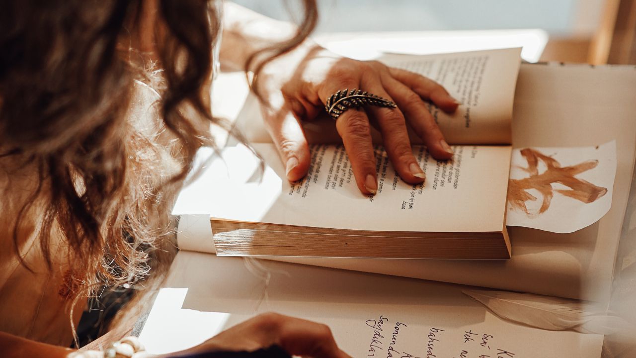 Uma mulher lendo um livro e escrevendo uma resenha