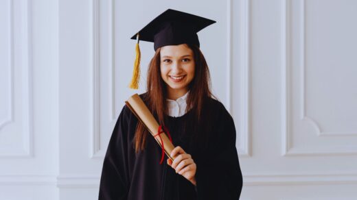 Jovem mulher com roupa de formatura segurando o diploma