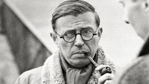 Uma foto preta e branca de Jean Paul Sartre fumando um cachimbo